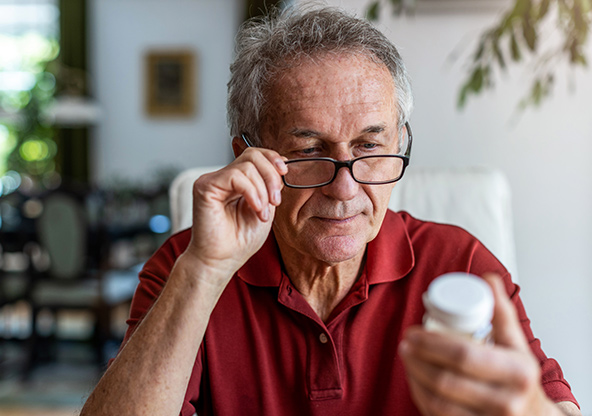 A senior man is reading the label on his medication bottle